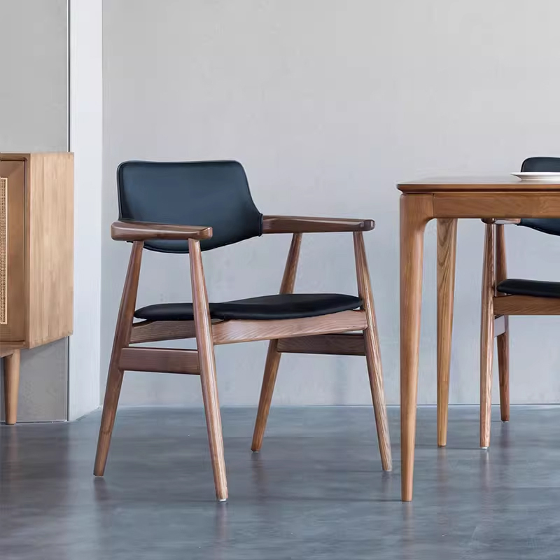 Side view of black leather dining chair with wooden frame and curved backrest