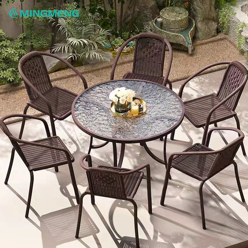 Brown outdoor wicker dining set with round glass table and six chairs for patio or garden
