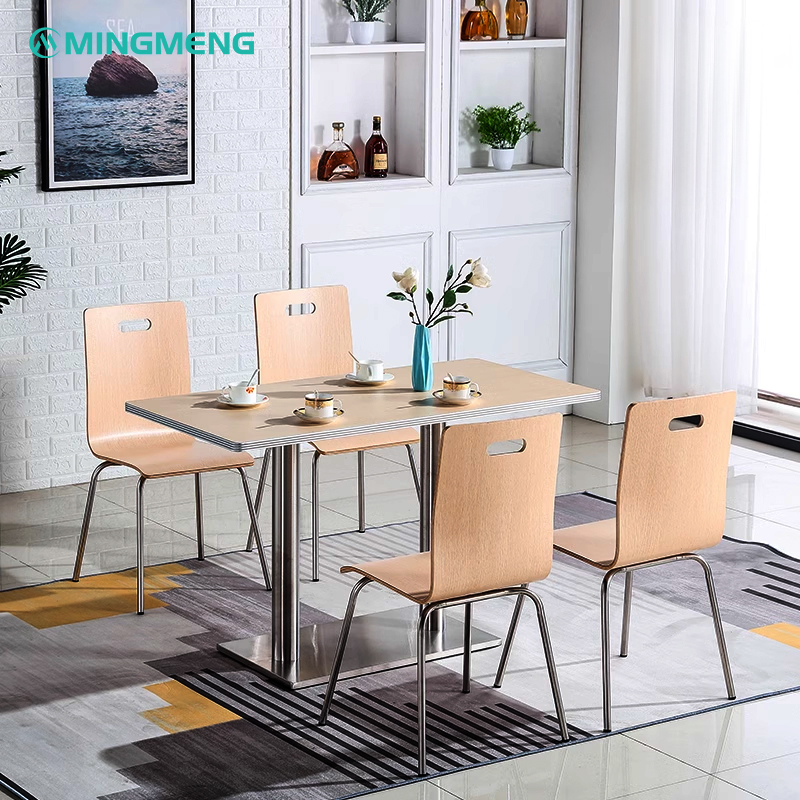 Modern canteen area with four bentwood chairs with metal legs arranged around a rectangular table on a patterned rug