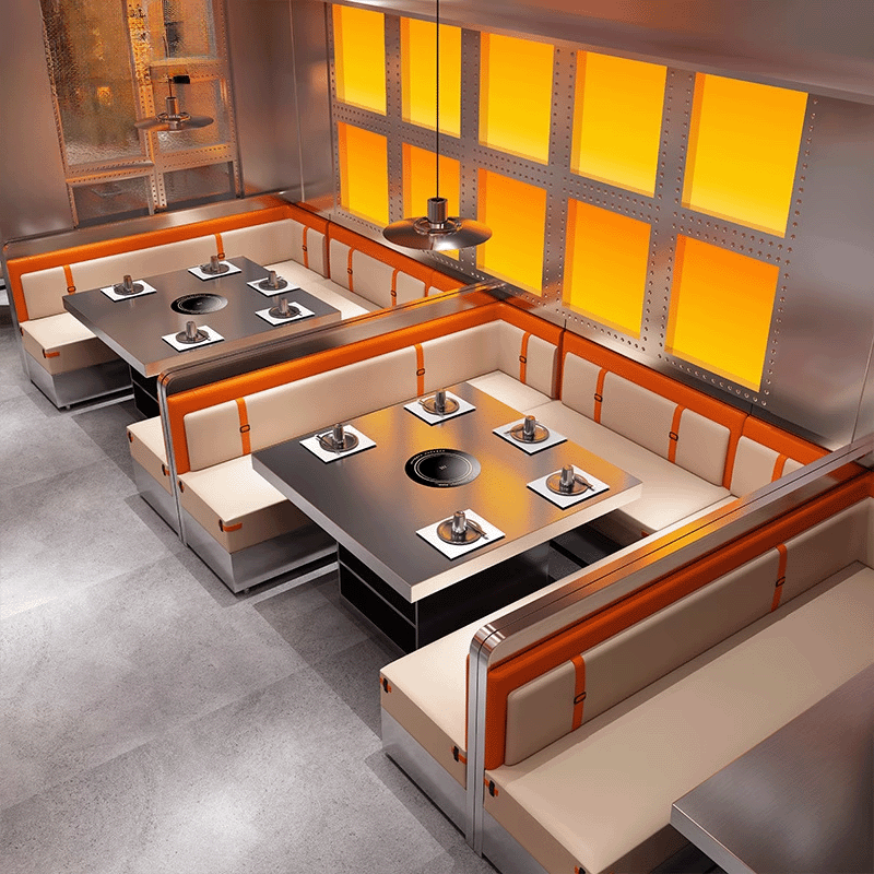 Spacious corner hotpot booth with cream and orange upholstery, arranged with induction steel tables under a yellow lit wall