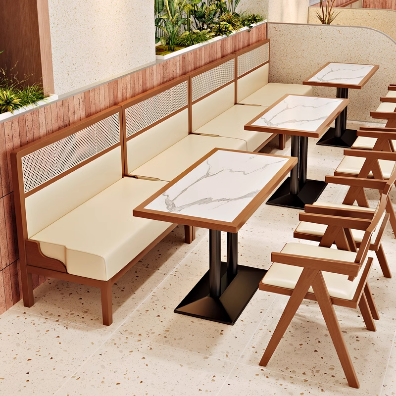 Extended wooden booth seating with rattan backrests and cream cushions paired with rectangular marble dining tables in a modern restaurant