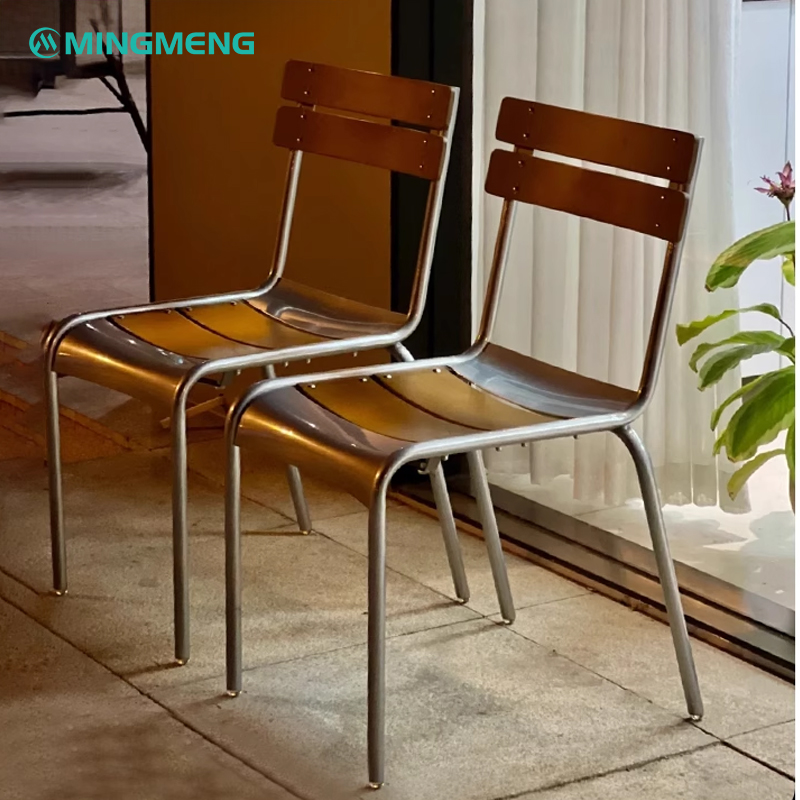 Pair of minimalist metal canteen chairs with bent wood seat and backrest, placed beside a window with soft lighting