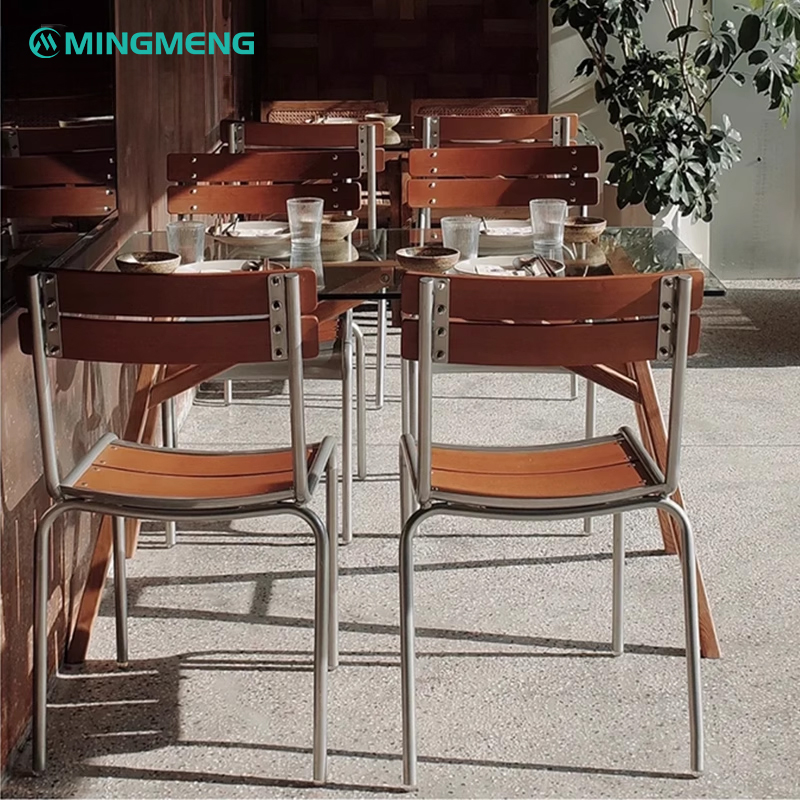 Retro-style metal canteen chairs with wooden slats arranged around a glass-top dining table in a restaurant setting