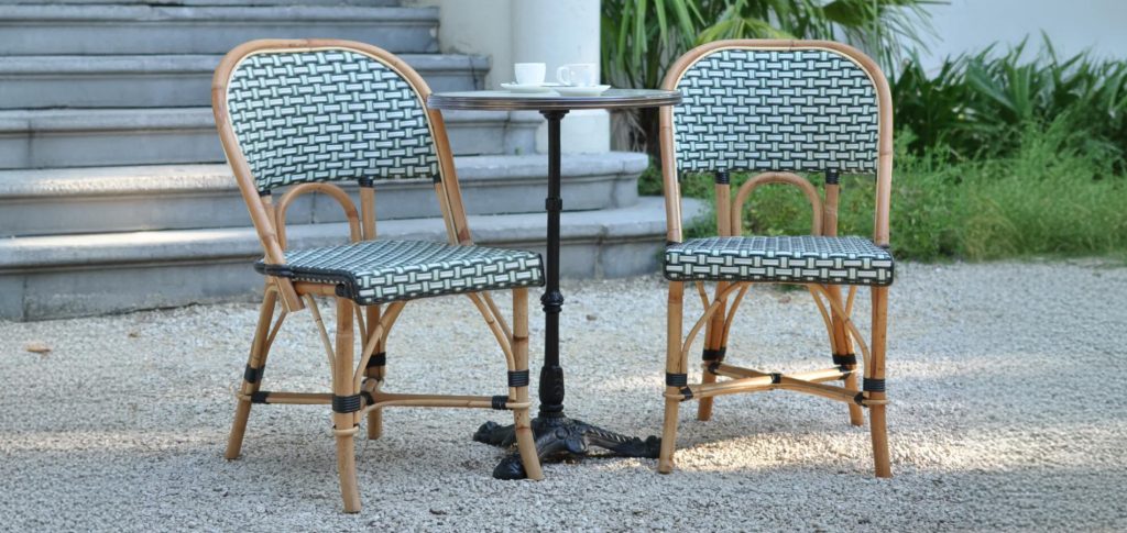 Rattan Restaurant Furniture: The Soul of Dining Spaces in 20252 Two modern outdoor rattan lounge chairs with woven backs and seats, paired with a round bistro table in a garden setting.