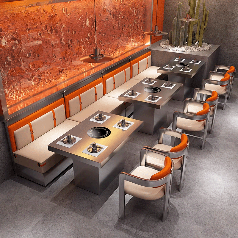 Futuristic hotpot restaurant setup with stainless steel armchairs and orange-accent booths along a textured red feature wall