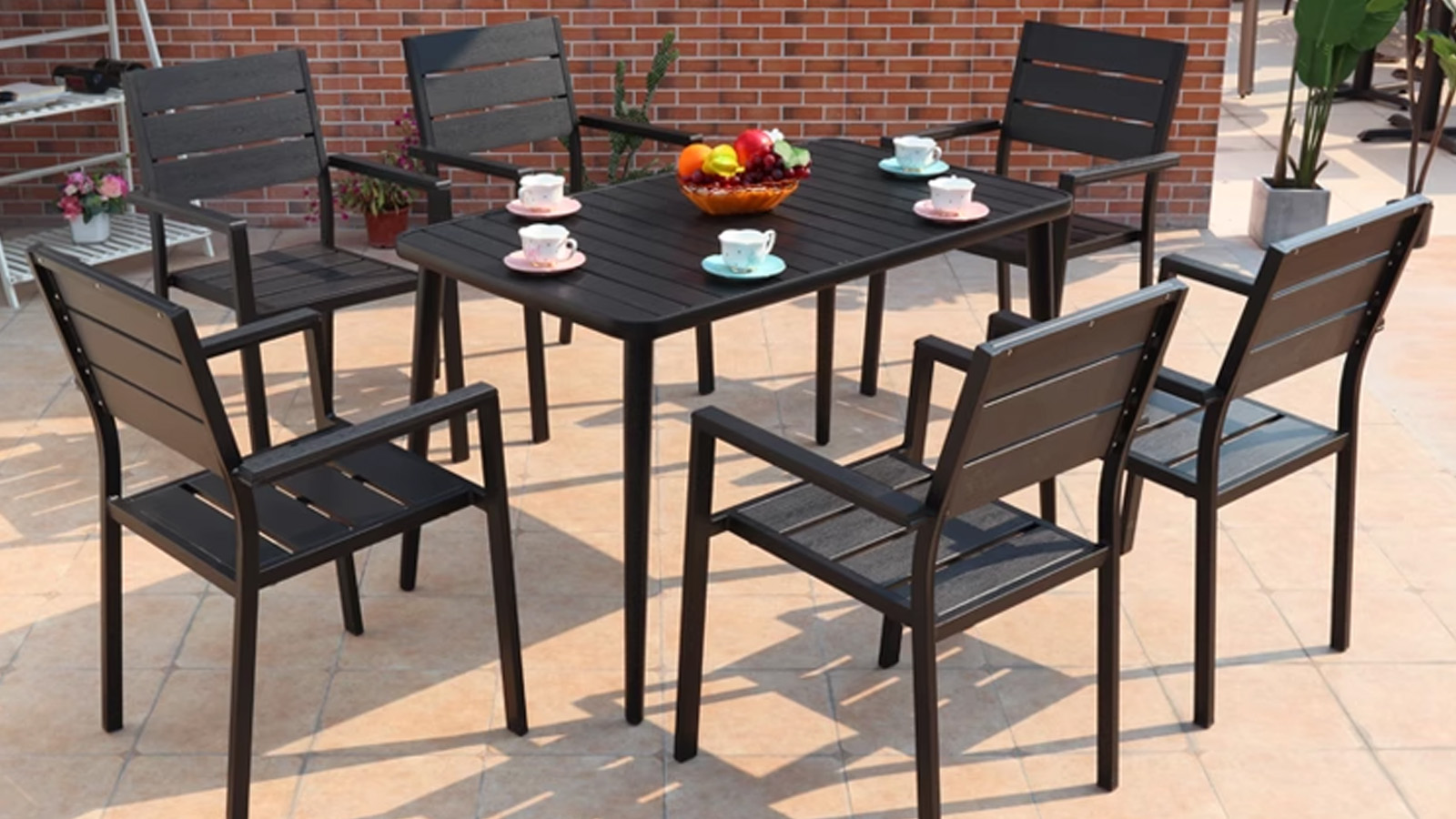 Black Plastic Wood Outdoor Armchair2 Outdoor dining table set with six black chairs and a colorful fruit bowl in patio environment