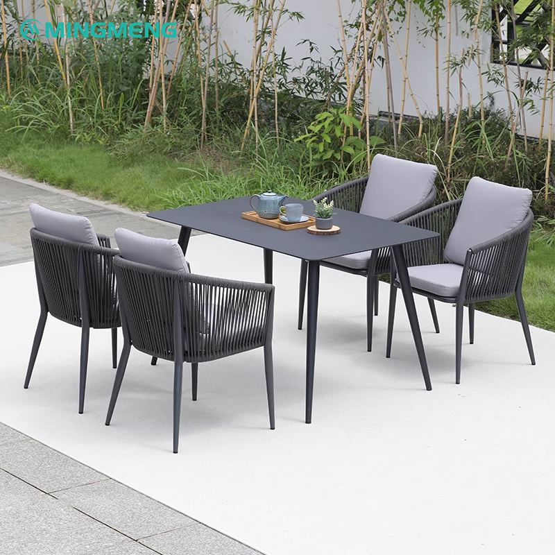 Black rectangular outdoor dining table with rope chairs and grey cushions