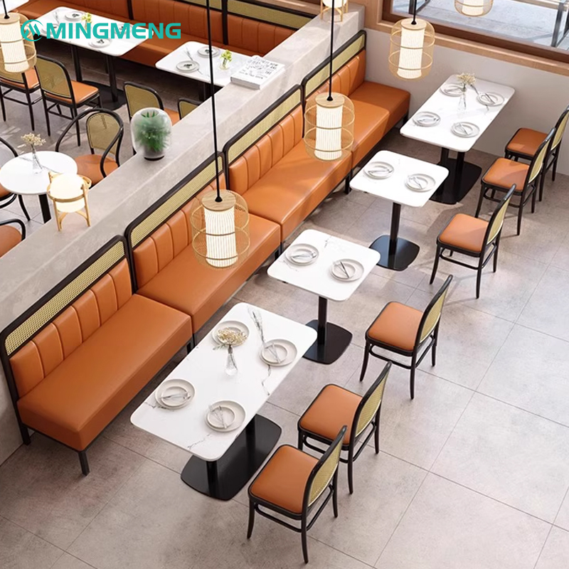 Stylish restaurant booth with cushioned seating and orange cushions along with matching tables