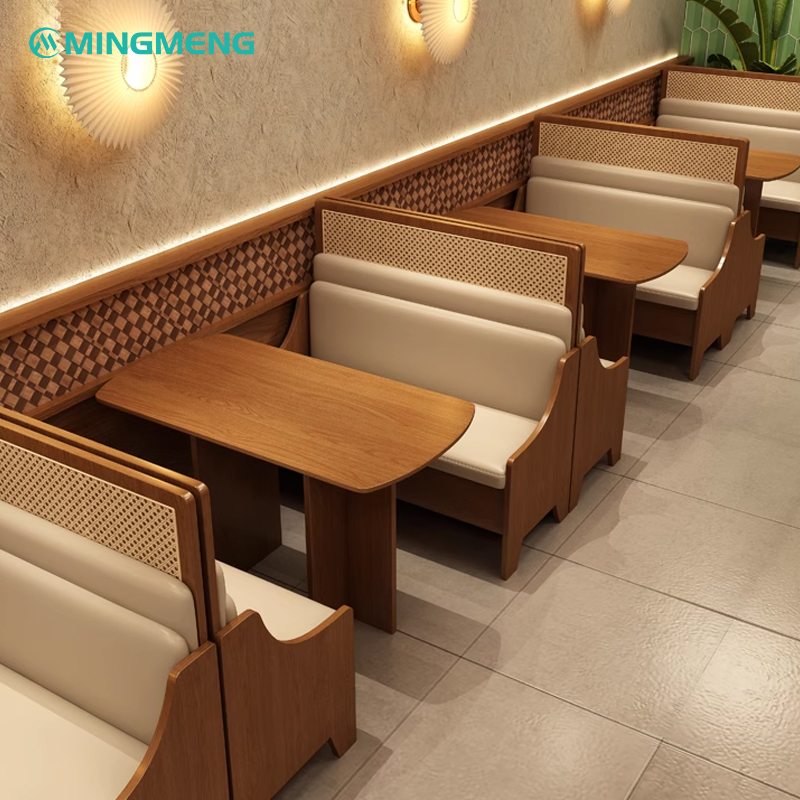 Restaurant booth seating with beige leather cushion, wooden table, and wall lamps