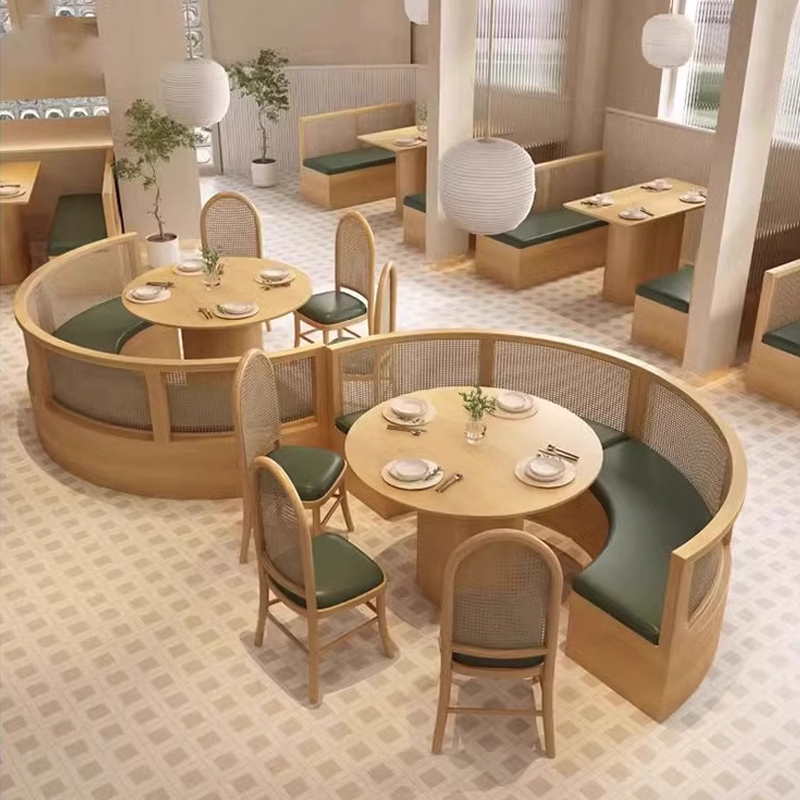 Round booth seating with woven rattan backs, green leather cushions, and matching wooden dining chairs in a softly lit restaurant interior