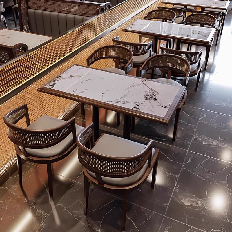 Elegant restaurant layout with sintered stone top tables and round-back rattan armchairs on dark marble flooring