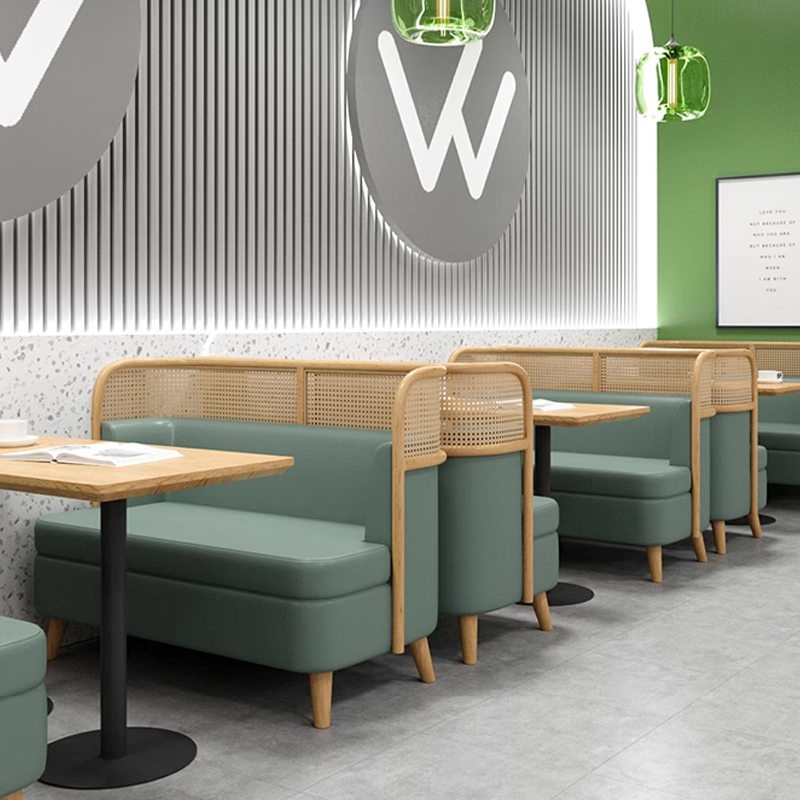 Green Faux Leather Restaurant Booth with Cane Backrest Comfortable green restaurant booth with wooden tables and chairs in a modern dining space.
