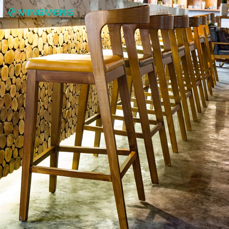 Wooden bar stool with brown leather seat and backrest, designed for bar settings.