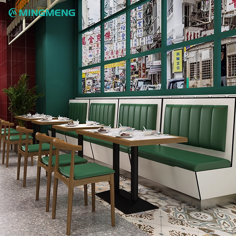 Green and white leather booth seating with wooden tables, providing a cozy and modern dining experience.