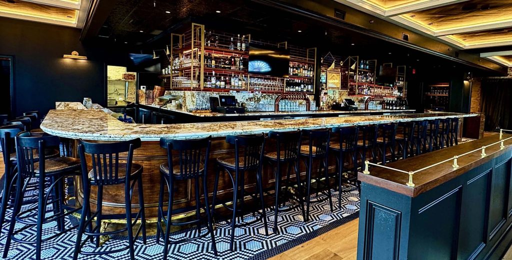 Row of classic black wooden bar stools with high backrests placed along a marble bar counter in a stylish bar interior.