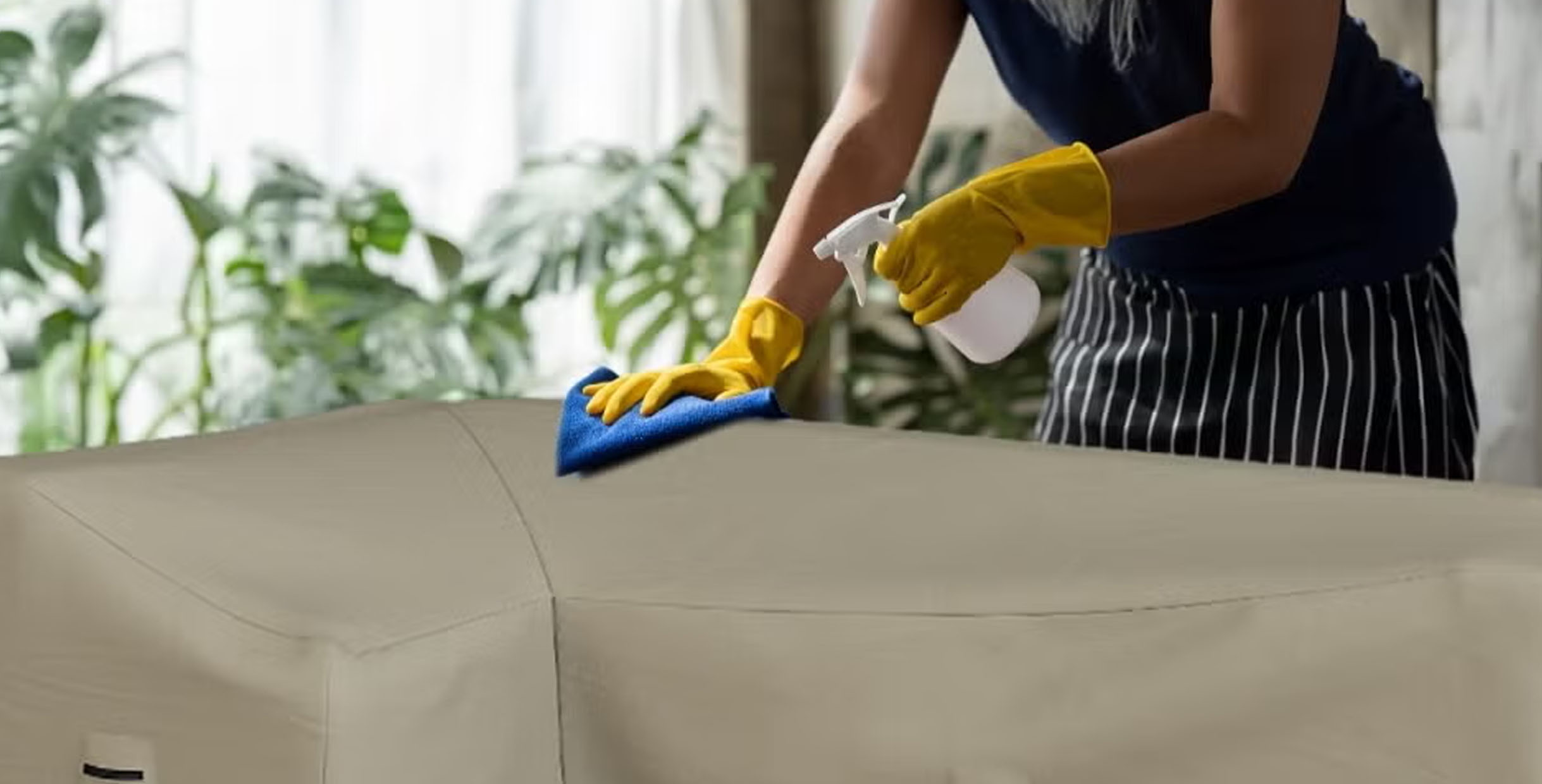 Person cleaning outdoor furniture with spray bottle and cloth
