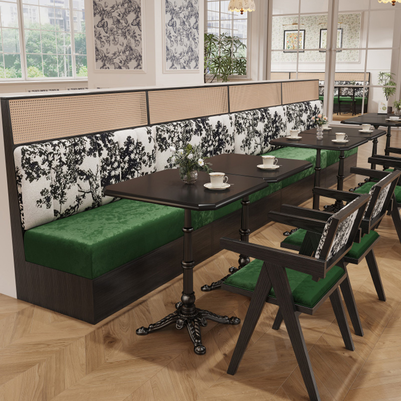 Elegant restaurant booth with green seats and black floral patterned backrest for stylish dining.