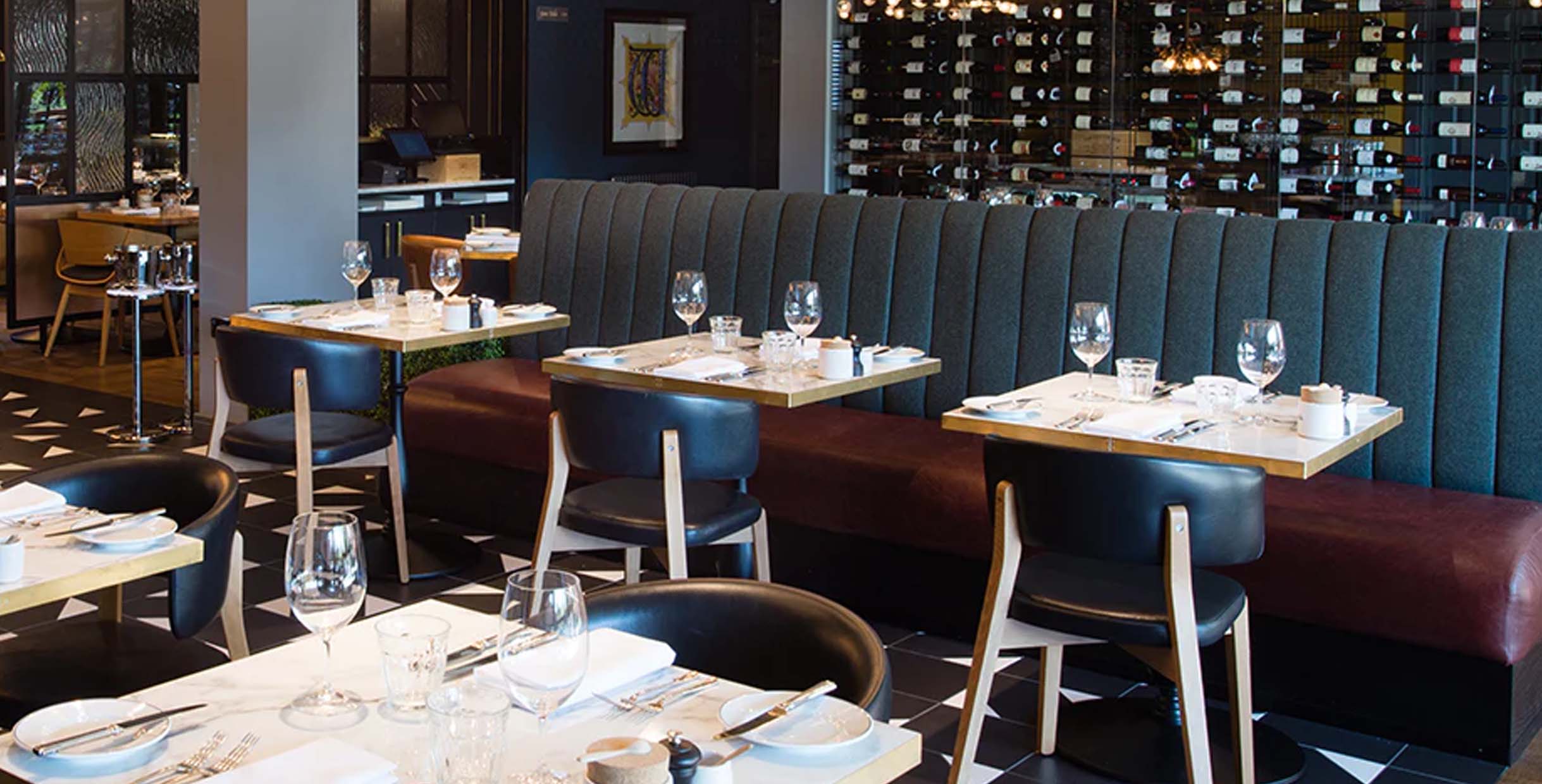 Modern restaurant booth seating with dark gray upholstery and leather accents, perfect for upscale dining settings.