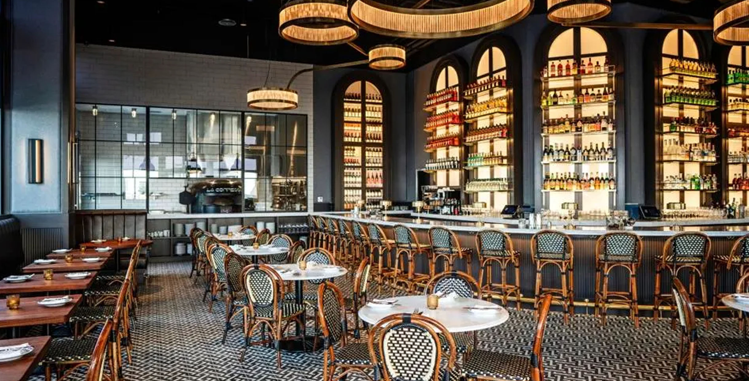 Elegant dining area with patterned flooring, rattan dining chairs, and a fully stocked bar
