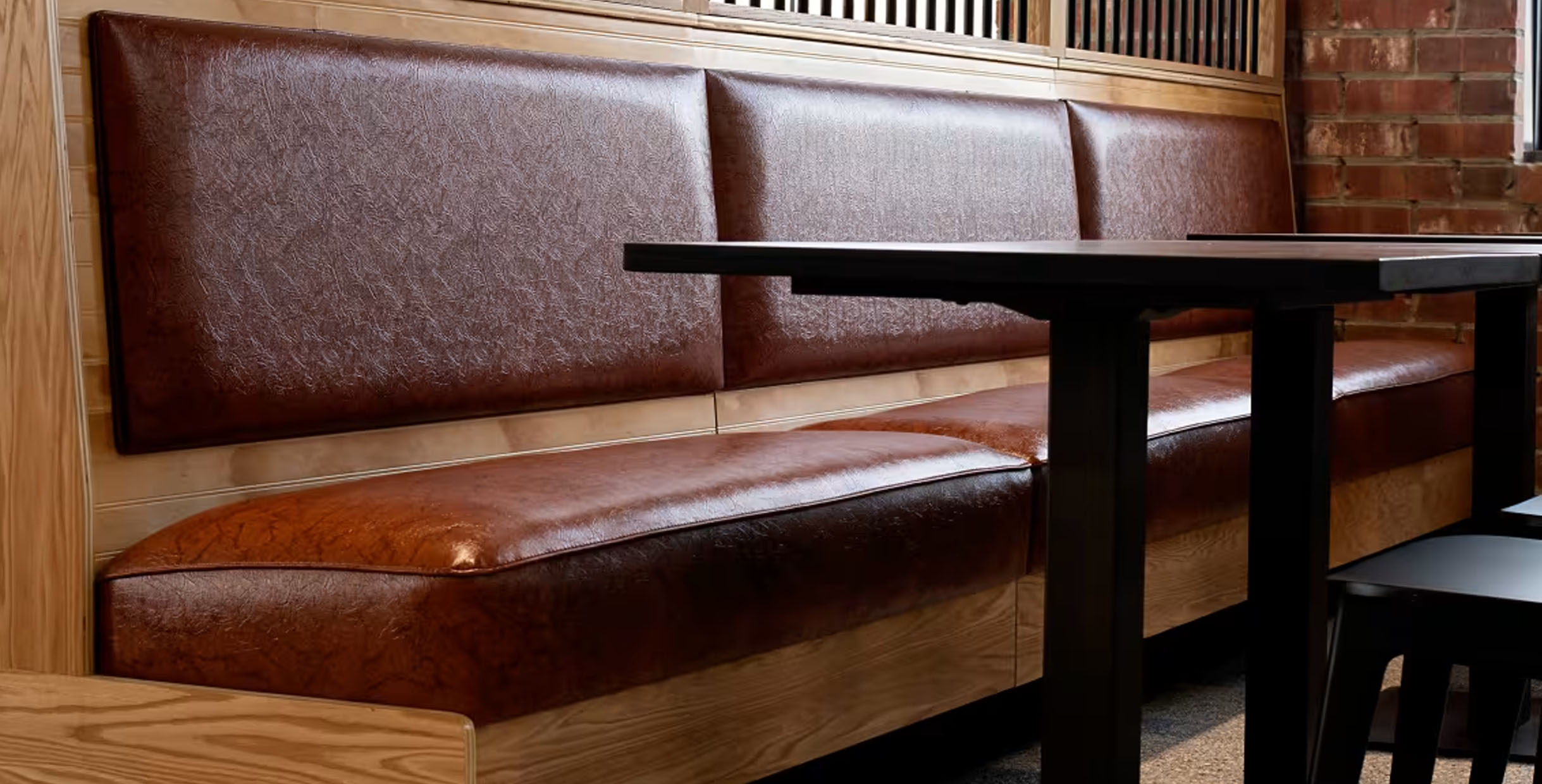 Brown leather booth seating at a restaurant with a sleek black table