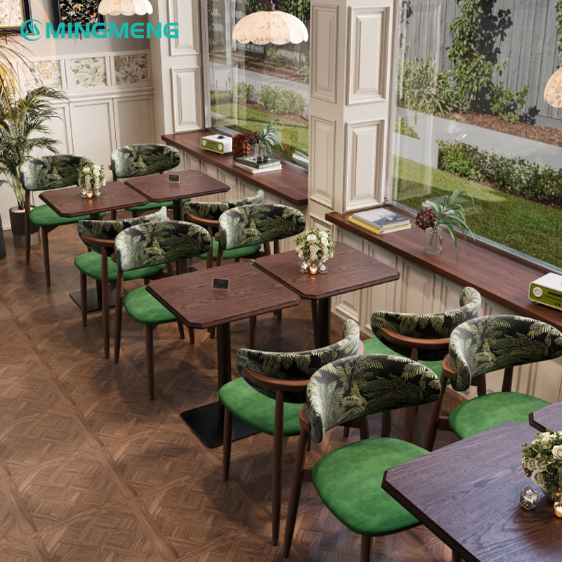 Retro horn restaurant chairs with green upholstered seats and palm leaf patterned backrests arranged around dark wooden dining tables in a modern restaurant setting.