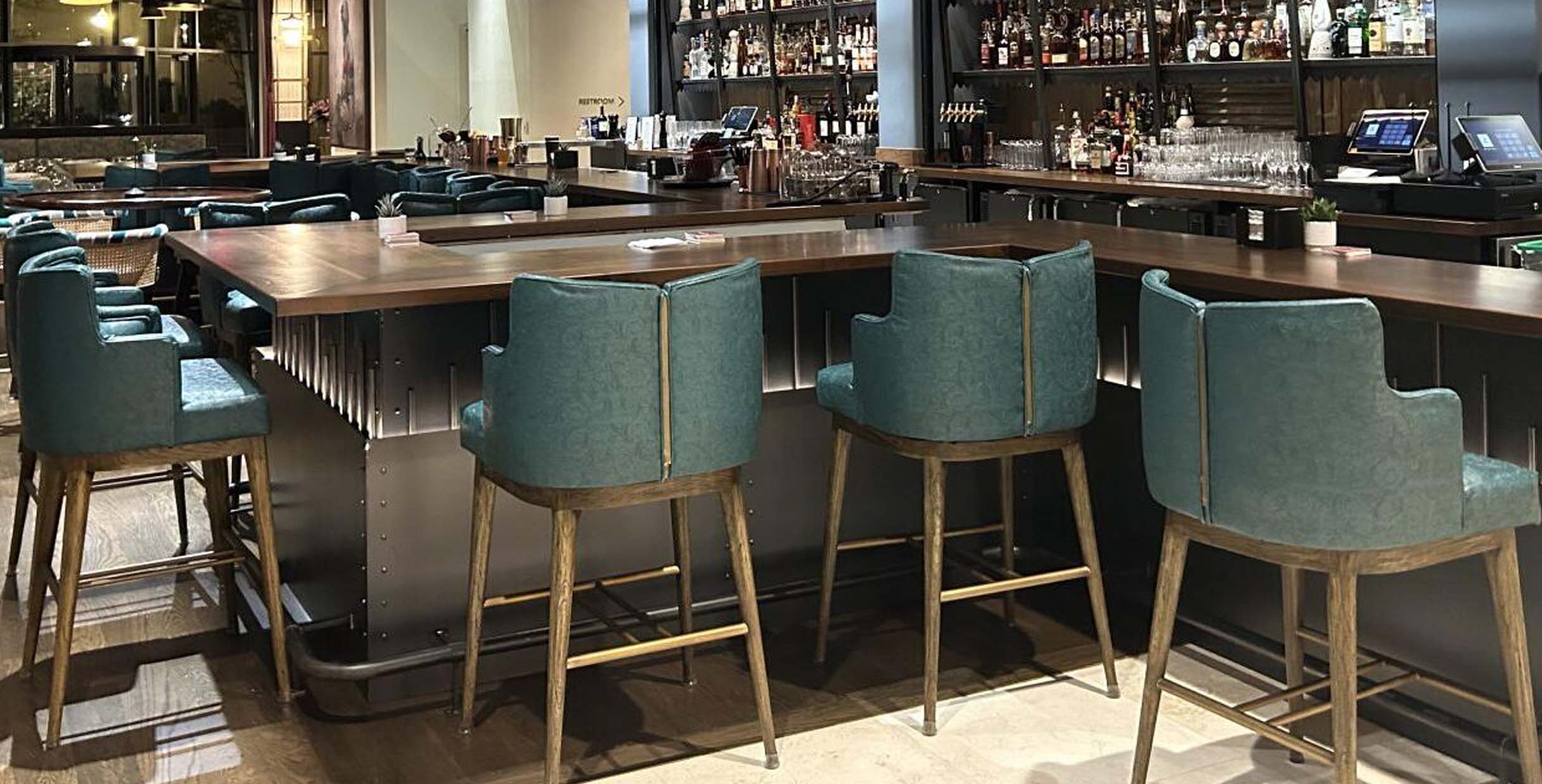 Buy Bar Stools That Match Your Style: Modern, Classic, or Industrial6 Teal upholstered bar stools with wooden legs and high backs placed along a modern wooden bar counter.