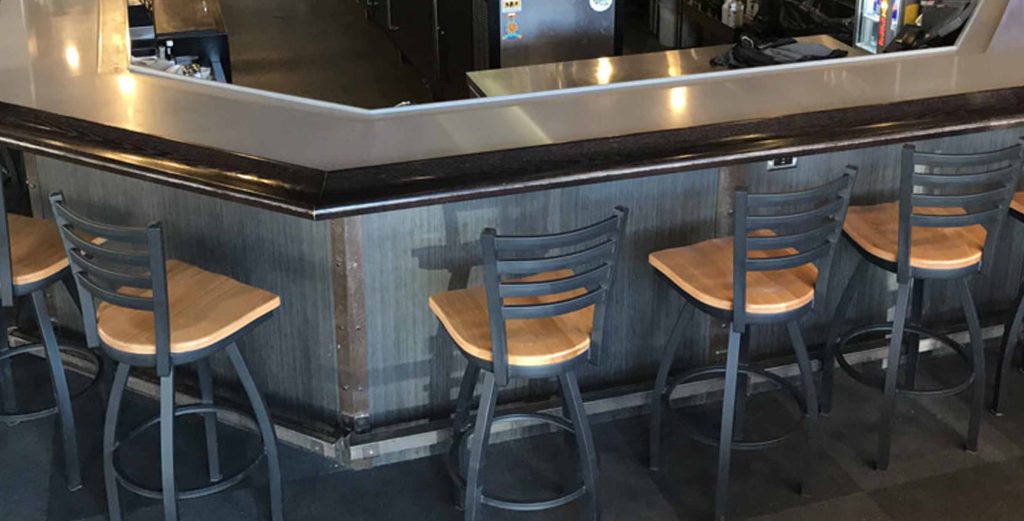 Commercial bar stools with metal frames and wooden seats arranged along a modern bar counter.