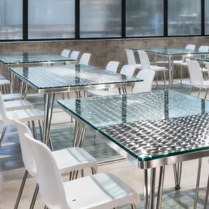 The Real Guide for Restaurant Owners: Choosing the Right Tabletop for Custom Restaurant Furniture7 Metal restaurant table with textured glass top and modern white dining chairs in contemporary café interior