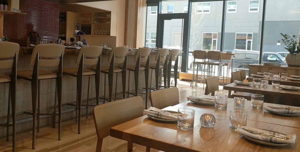 Restaurant interior with MINGMENG wooden dining tables and beige upholstered bar stools