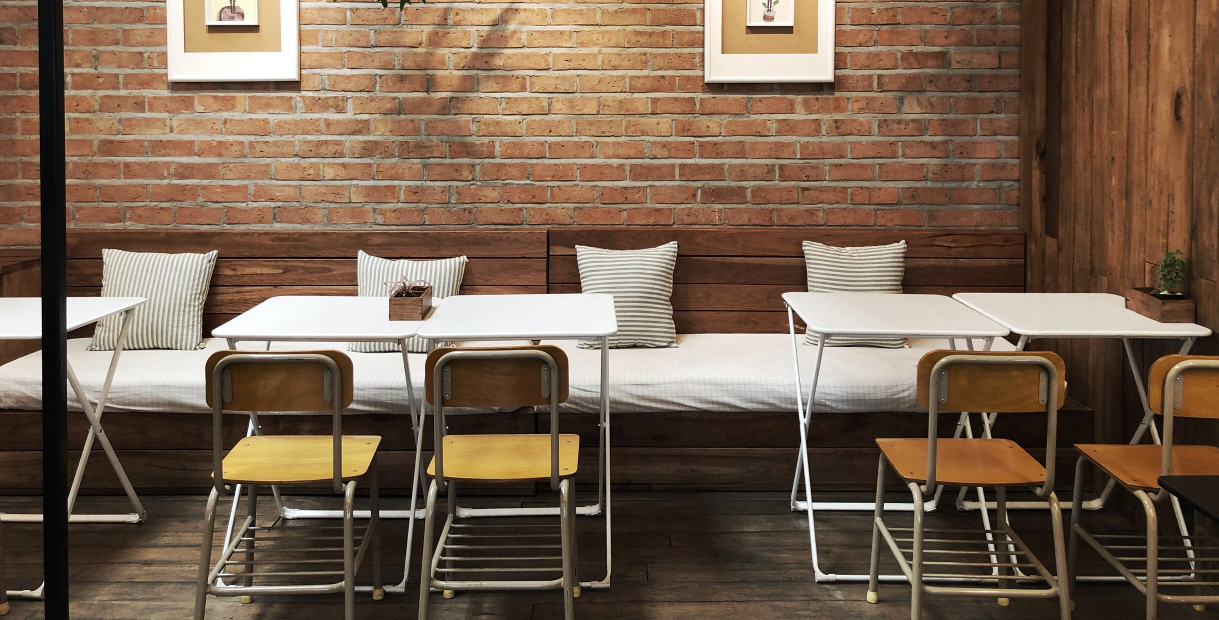 Mingmeng café table and chair sets with white metal frames and wooden seats in rustic brick-wall coffee shop interior