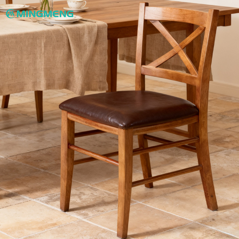 Classic X-Back Solid Wood Restaurant Chair1 Mingmeng classic X-back solid wood restaurant chair with brown leather cushion displayed in a warm dining room setup with a wooden table and linen tablecloth.