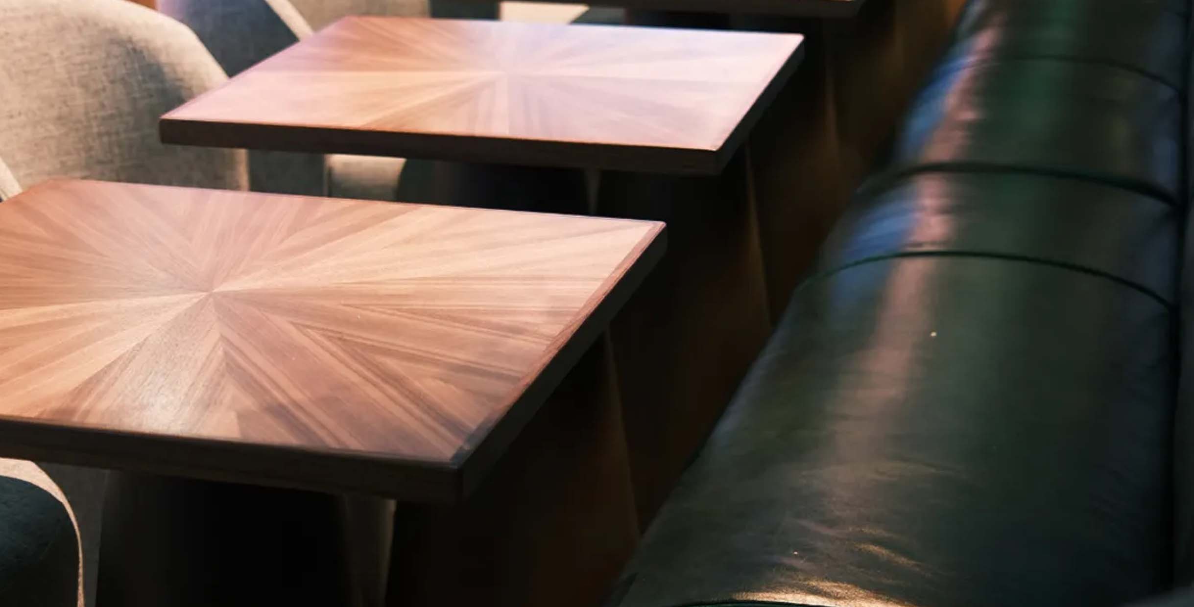 How to Source Commercial Restaurant Supplies Furniture Directly from Factory5 Close-up view of a Mingmeng restaurant dining table featuring a geometric wood veneer top paired with upholstered booth seating and metal frame chairs.