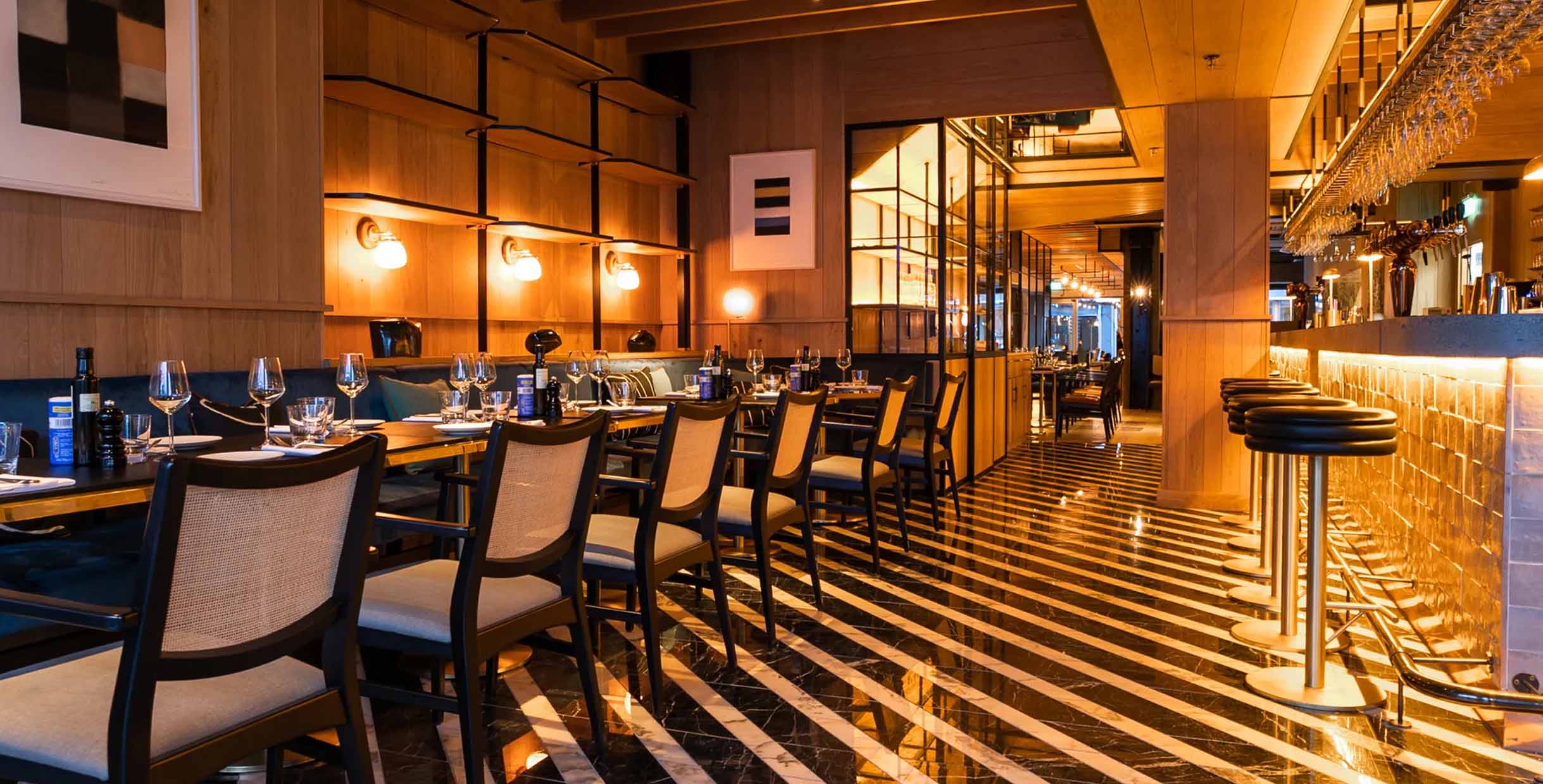 Modern restaurant interior with MINGMENG dining chairs and bar stools in a warm wood and leather design