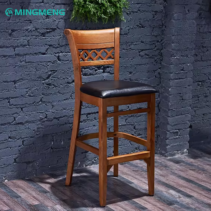 Vintage Dark Walnut Bar Stool Mingmeng wooden bar stool with cushioned black leather seat and lattice backrest, styled in an industrial restaurant setting with dark brick walls and wooden flooring.