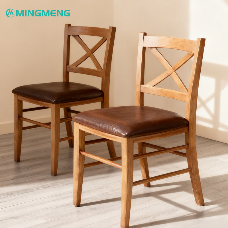 Classic X-Back Solid Wood Restaurant Chair2 Two Mingmeng X-back solid wood restaurant chairs with brown leather seats placed in a bright dining room, showcasing craftsmanship and natural wood texture.