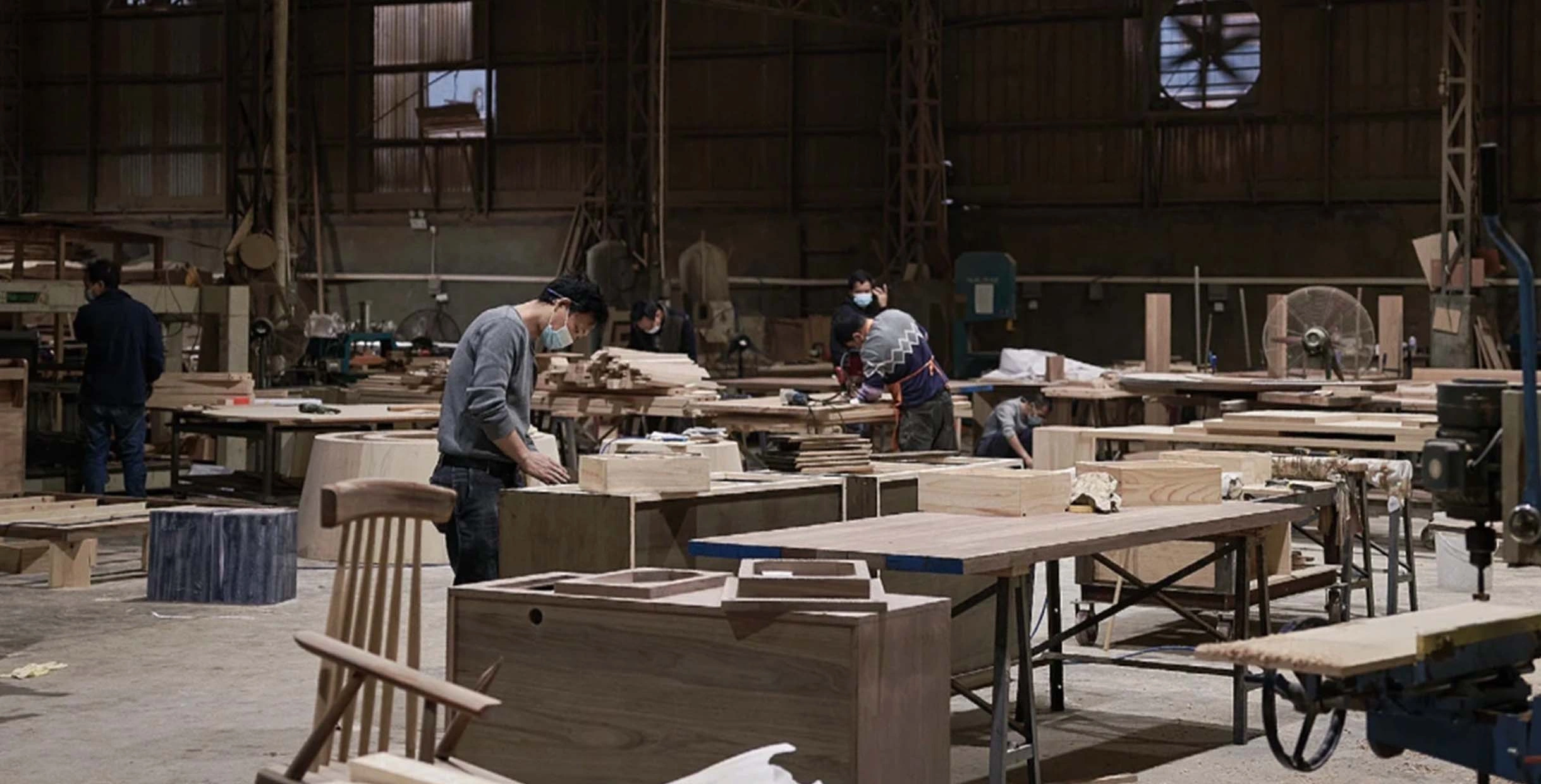 Craftsmen assembling contemporary restaurant chairs and tables in Mingmeng’s modern furniture factory workshop.